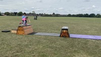Girl jumping over old fashioned gym vaulting equipment set out in a large field preview