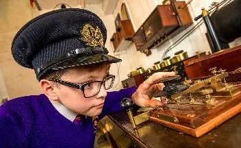 Young boy wearing hat playing with historic item