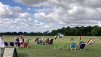 Large open field with people relaxing in brightly coloured deckchairs preview