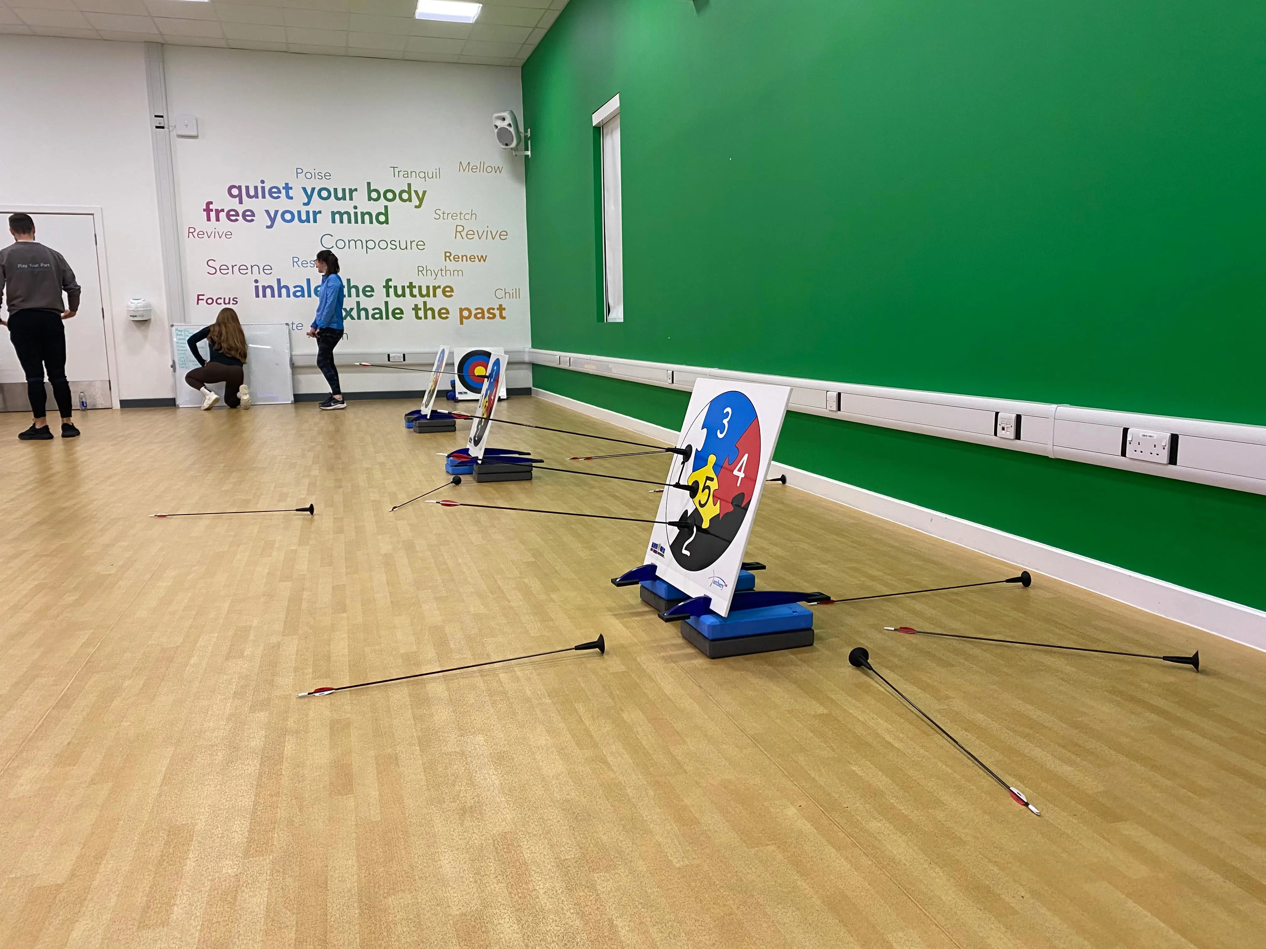 Plastic arrows stuck to an Archery target, part of an indoor archery session in a fitness studio