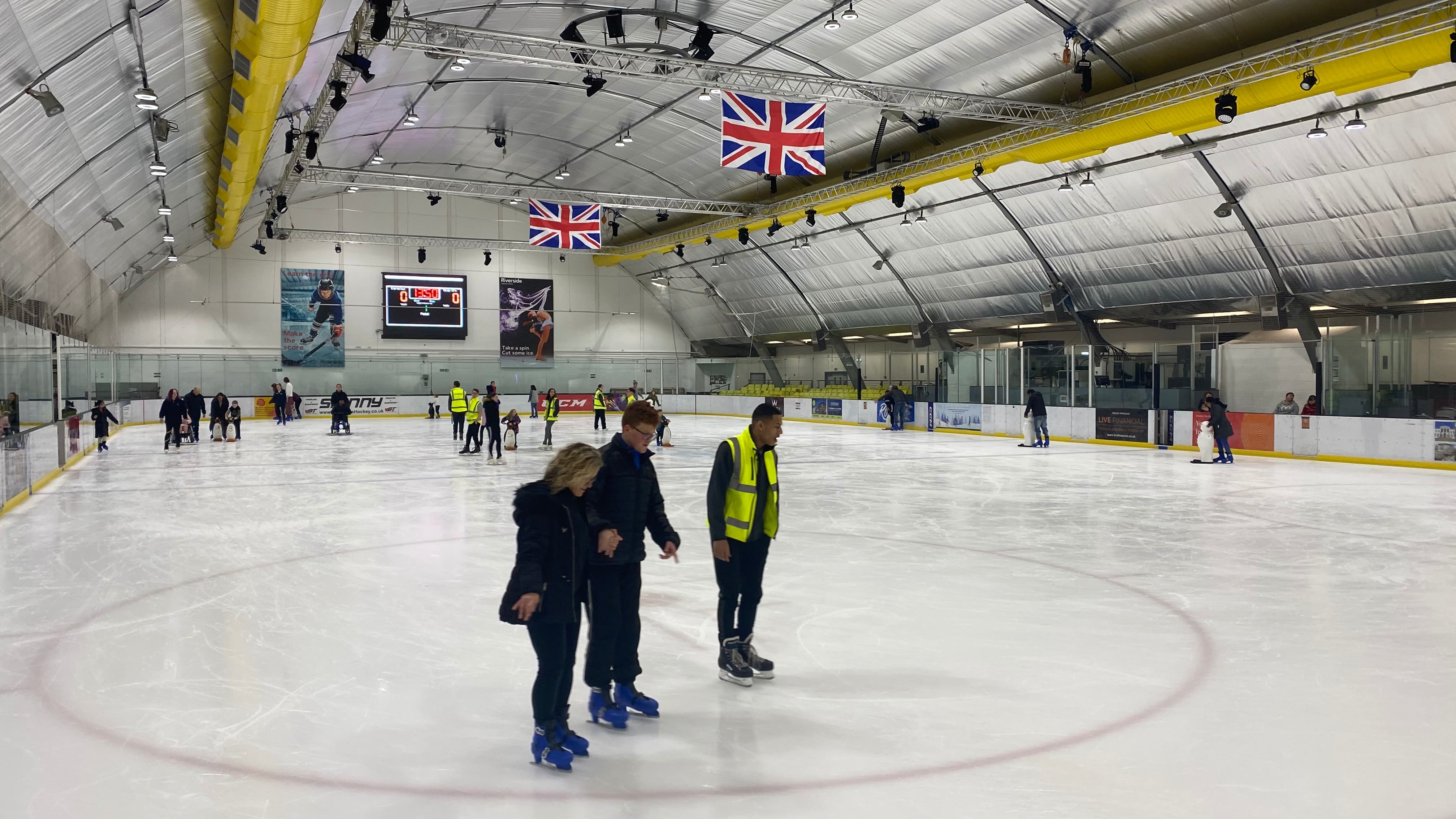 People in high visibility jackets helping others to learn how to ice skate preview