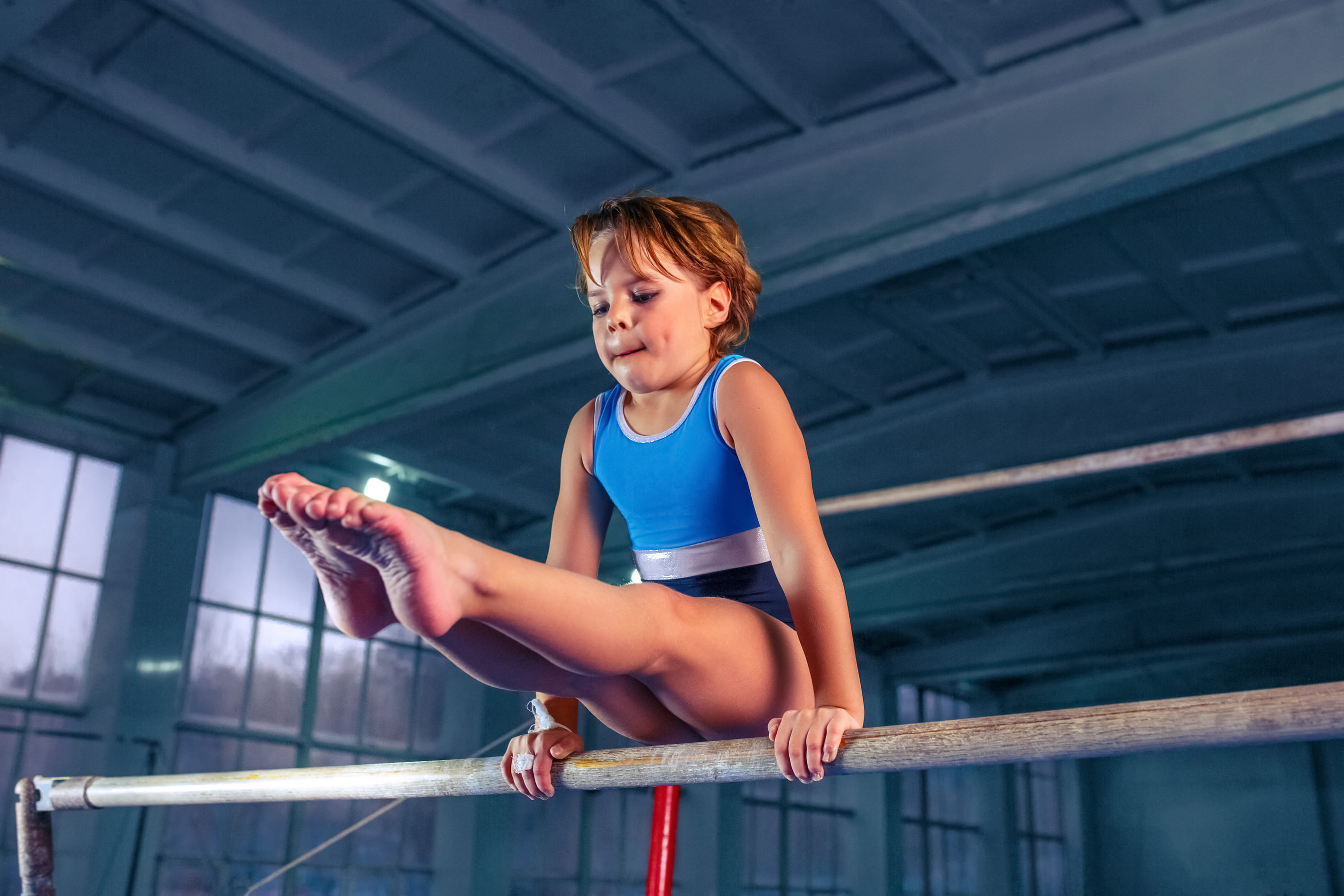 Child balancing in pike position on lower bar of asymmetric bars 
