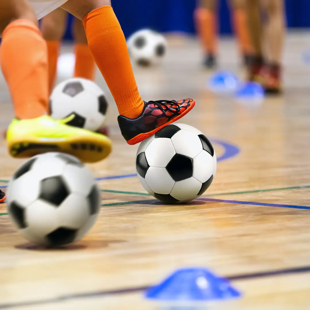 Children in sports hall doing football drills