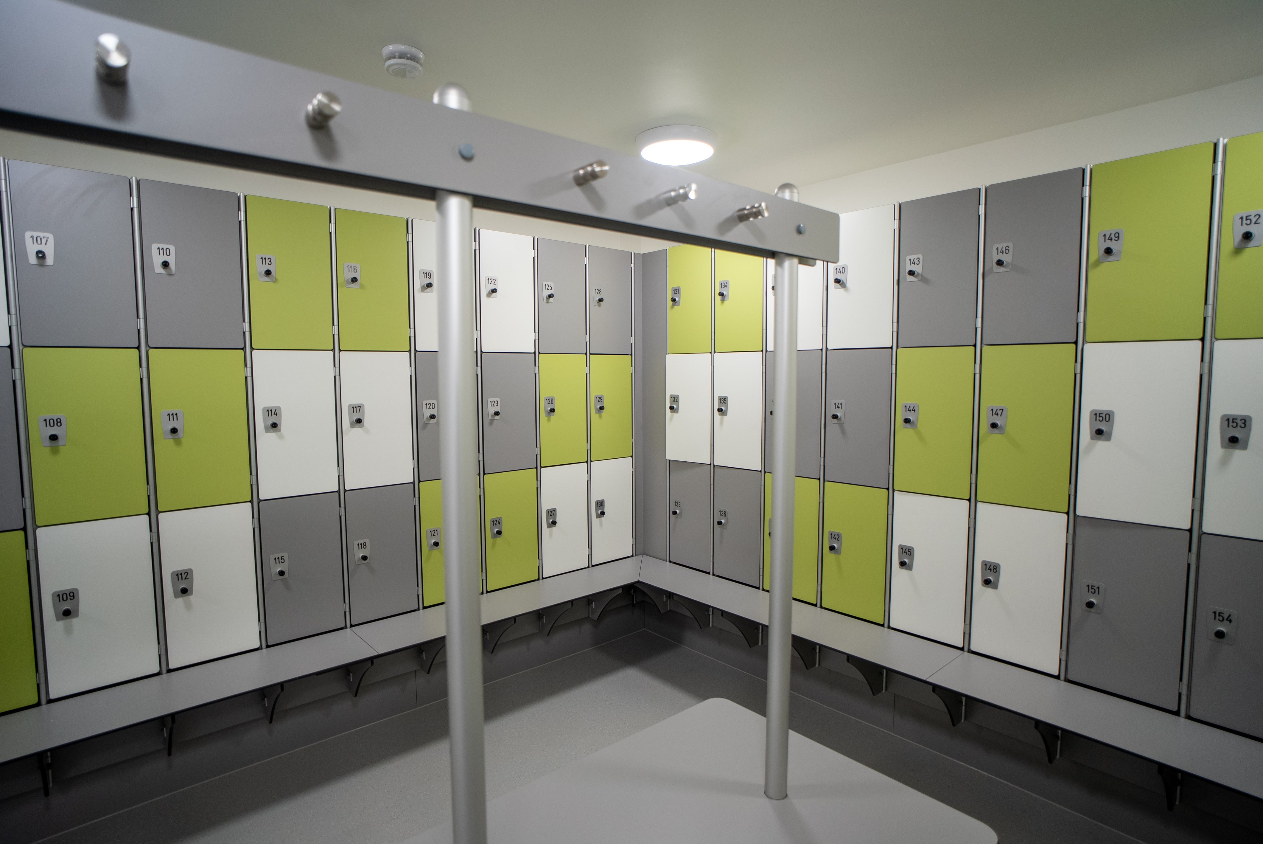 Clean, bright chaning room with central bench in the middle and lockers around the wall