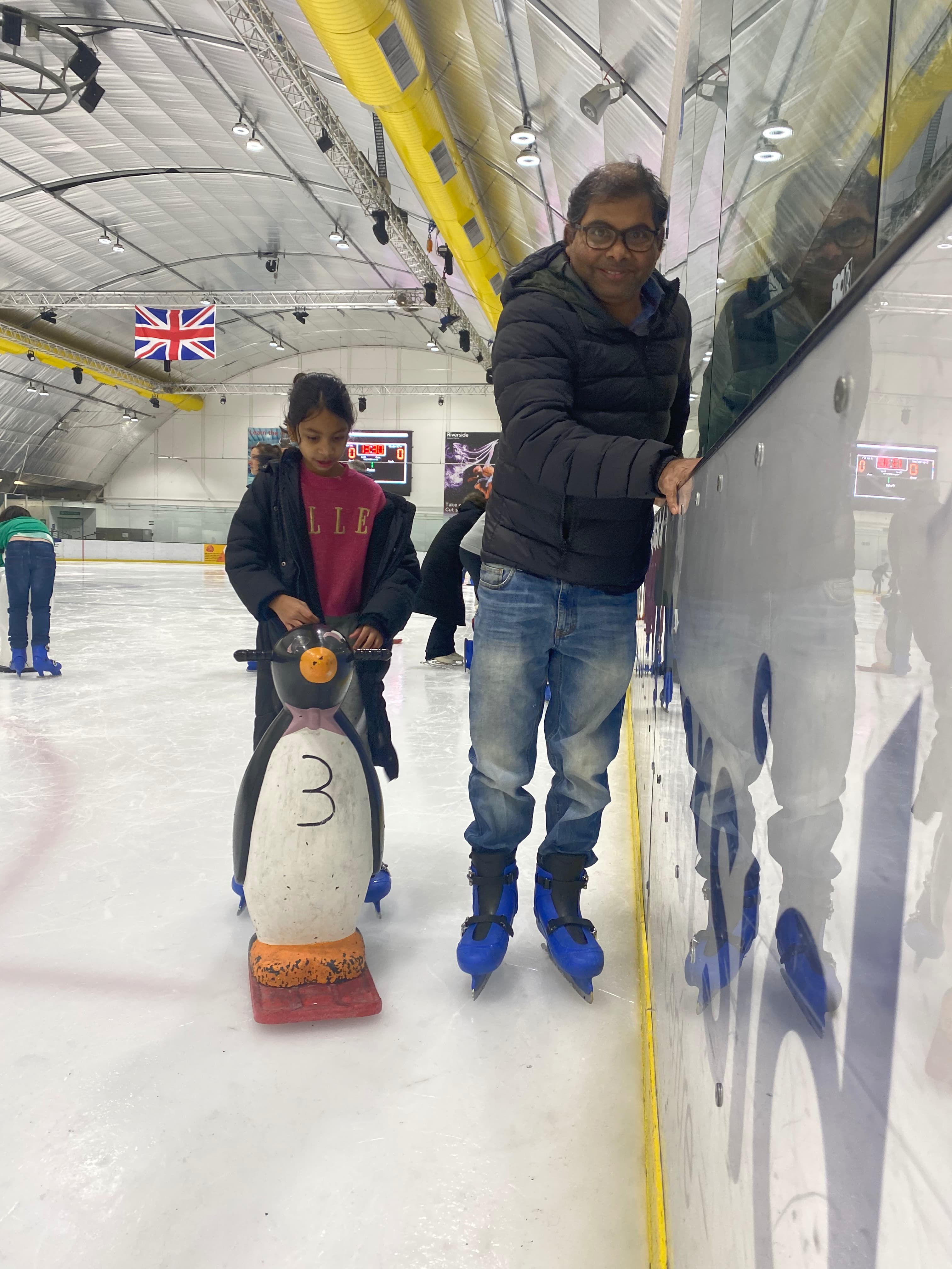 Father and daughter learning to ice skate, smiling. preview