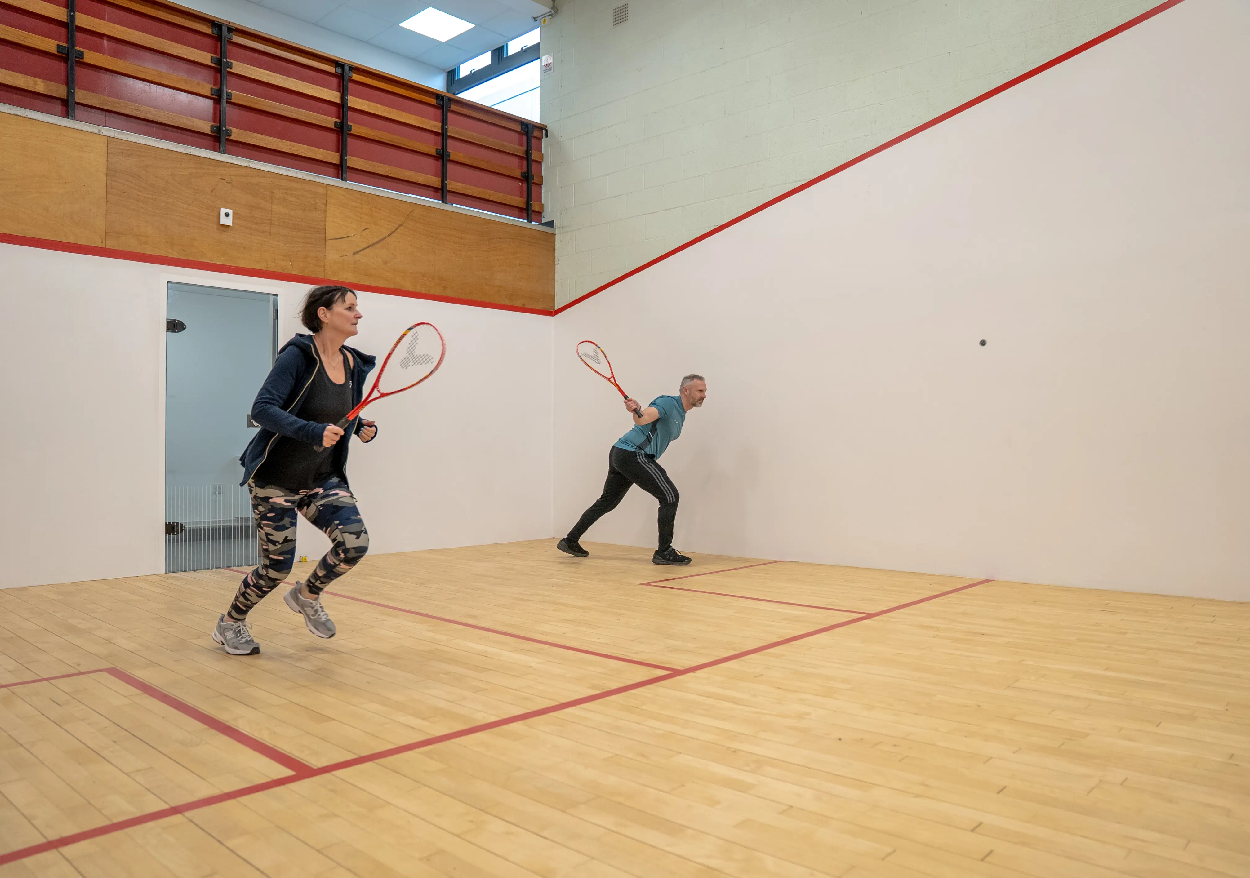 Man and woman playing on squash court