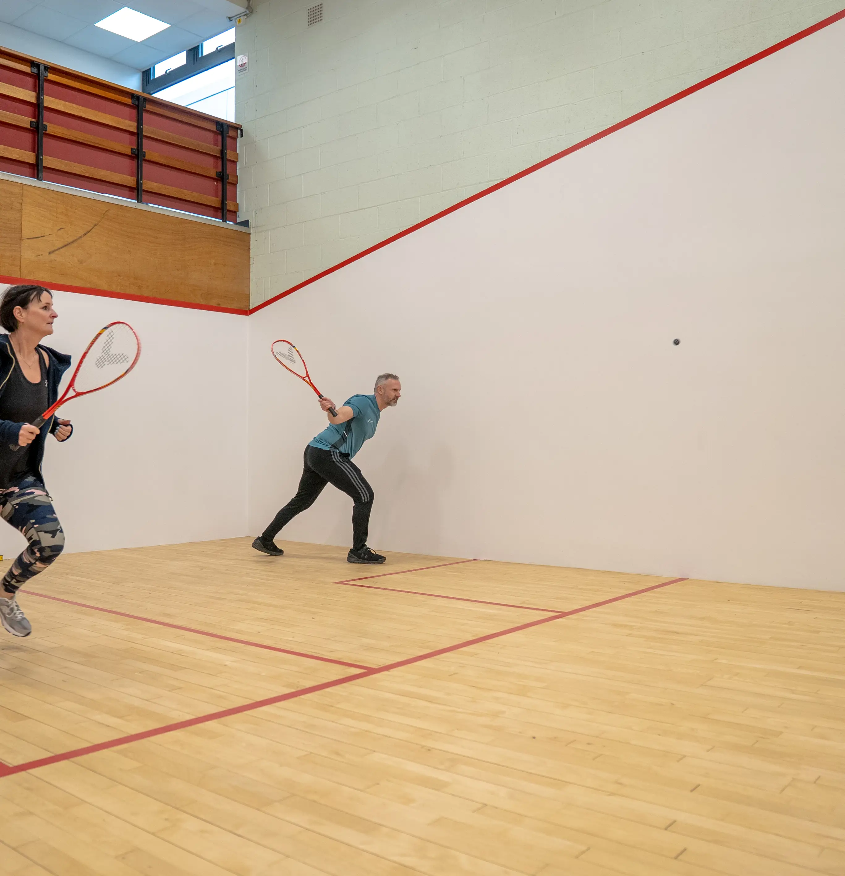 Man and woman playing on squash court
