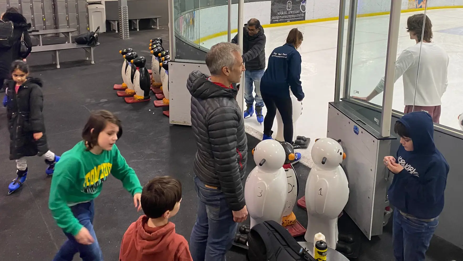 A small group of people entering an ice skating rink
