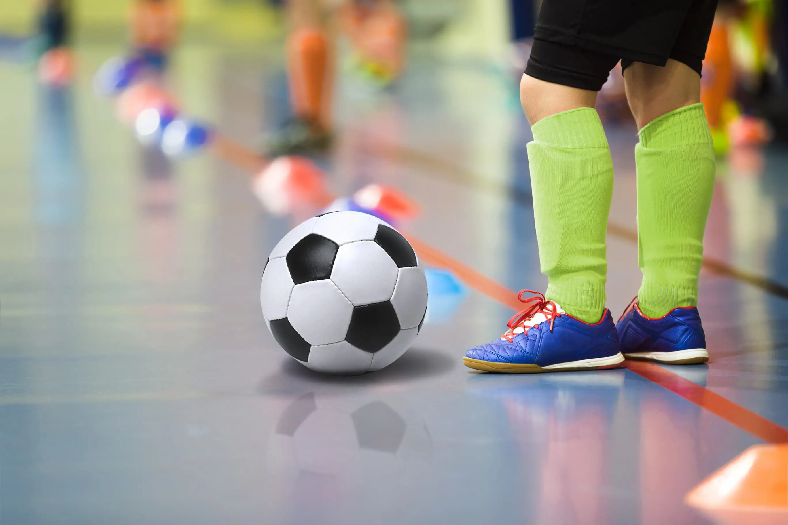 Young footballer's feet on a sports hall waiting to shoot a football