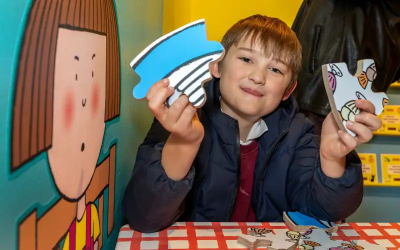 A young boy holding up puzzle pieces. 