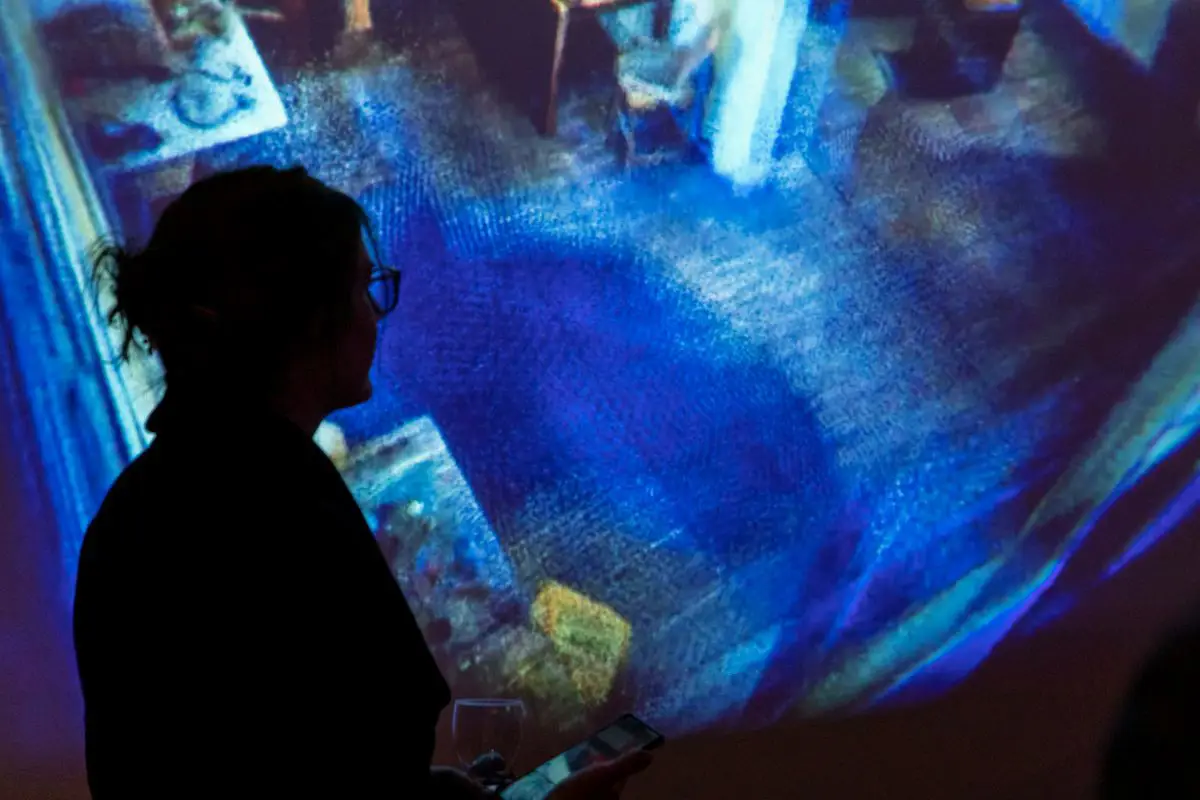 A woman standing in front of a screen with a projection of the scan of the Writtle Hut interior. 