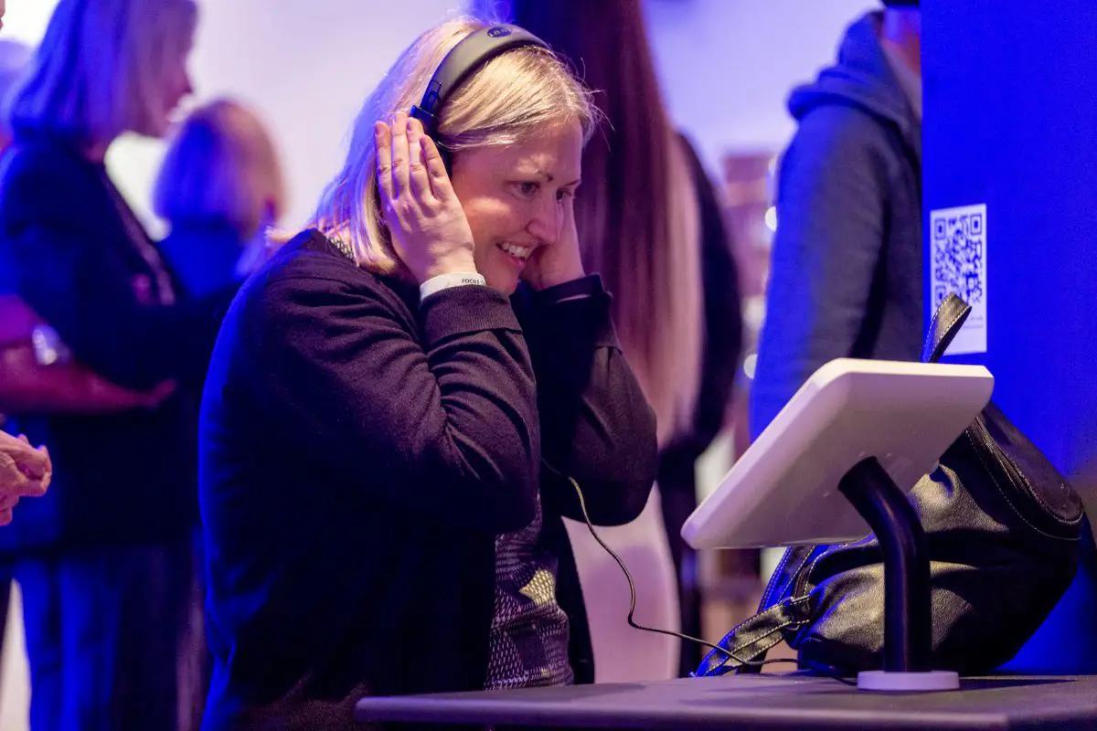 A woman wearing headphones and looking at a tablet at the Forecast22 launch. 