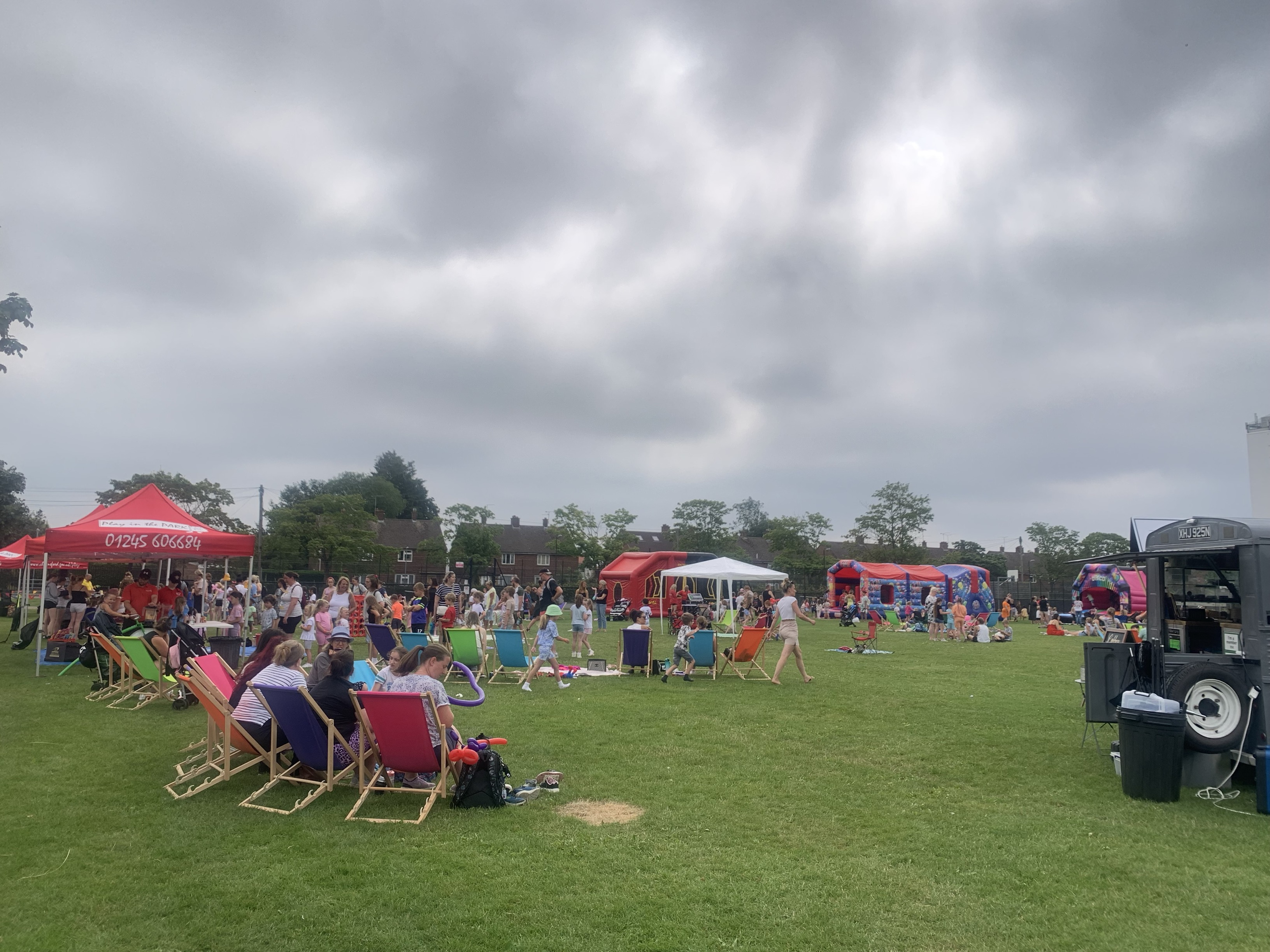 Lots of people in a park with gazebos and deckchairs having fun