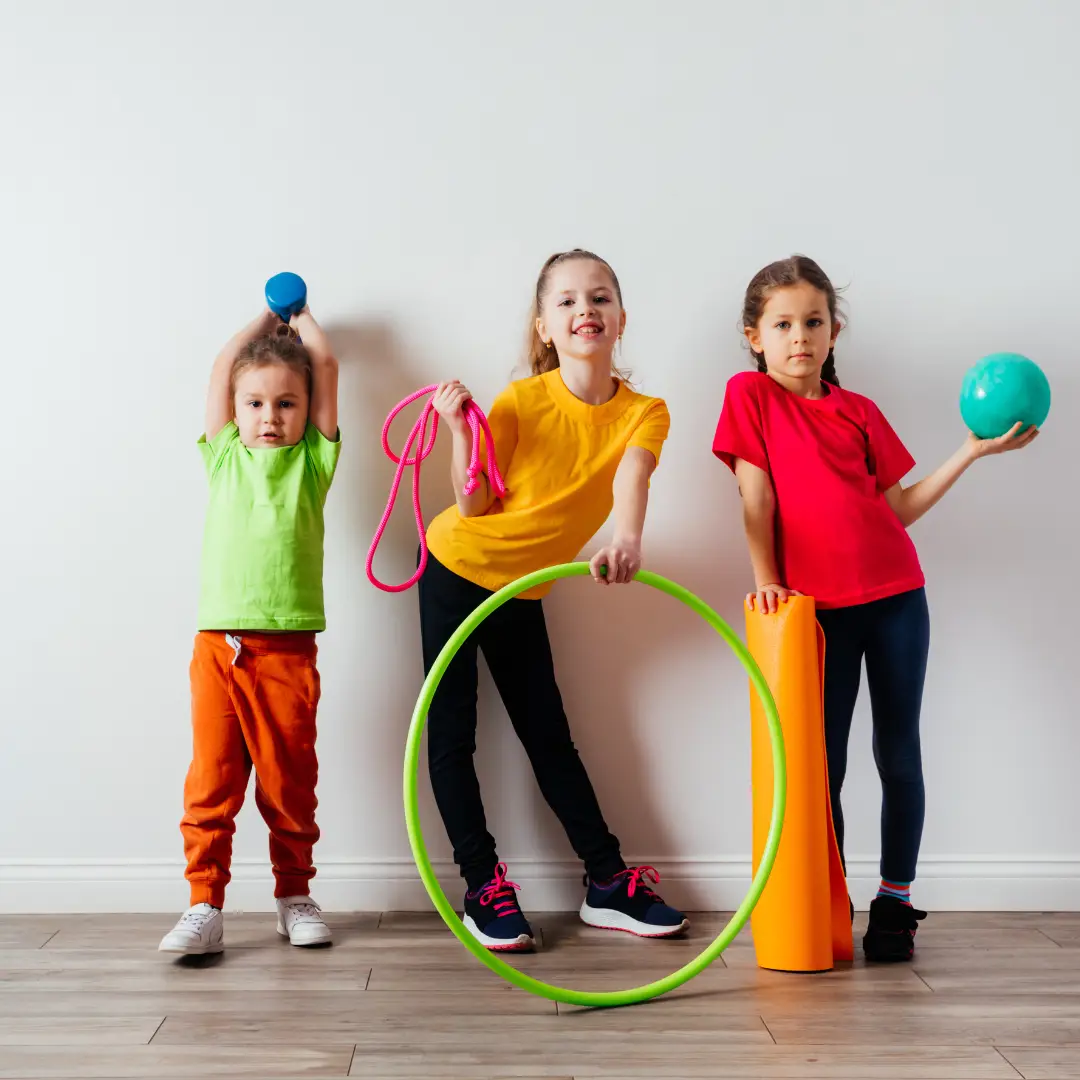 Three young children with play equipment, including hoops, ropes and balls