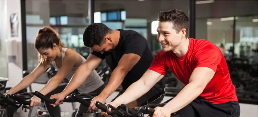 Three people take a group cycling class