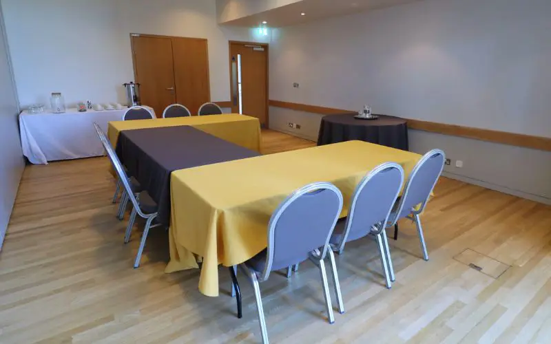 The Wells Suite set up with a small u-shaped table and a coffee station off to the side. 