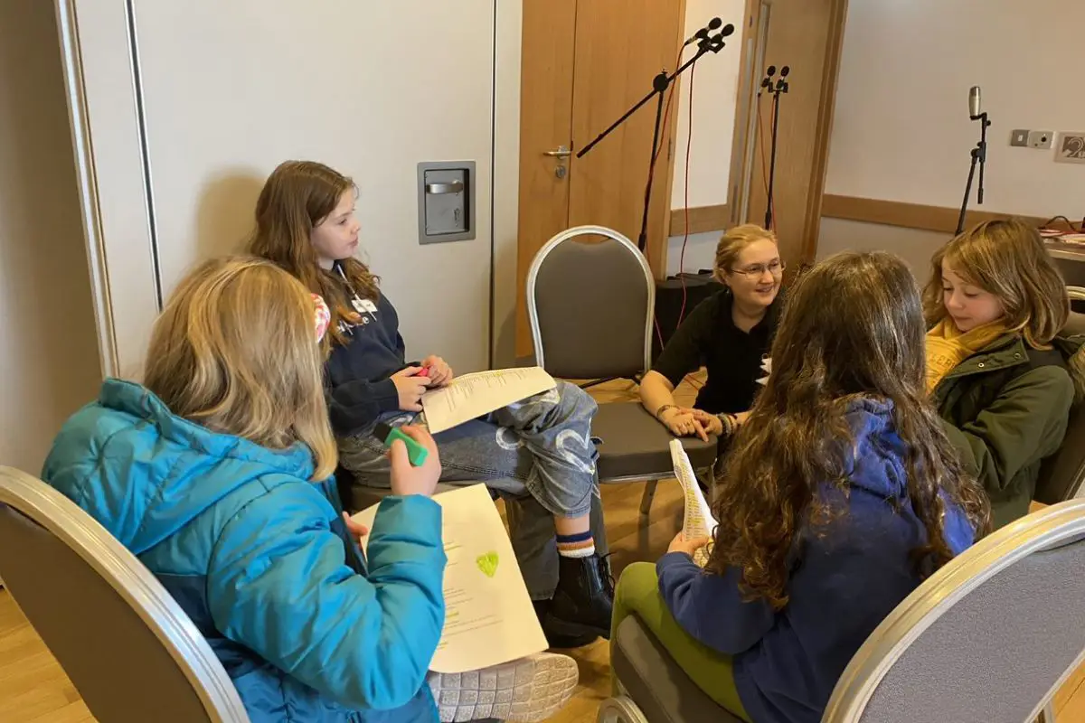 A group of kids at Radio Club sit in a circle working on their scripts. 