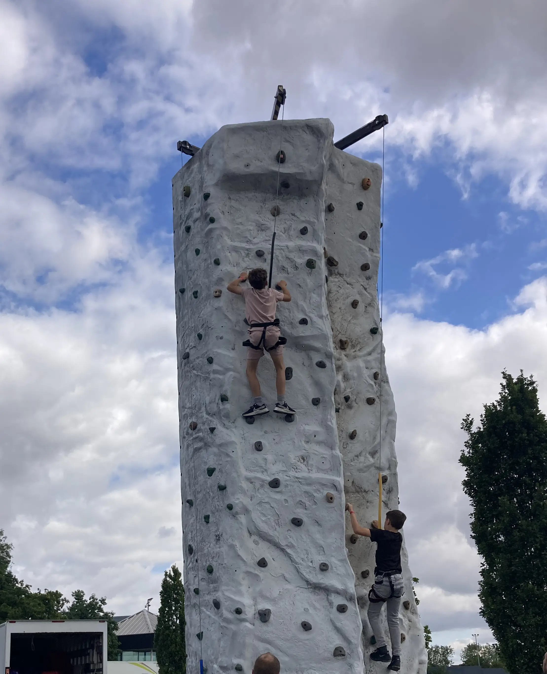 Children climbing large grey vertical climbing wall